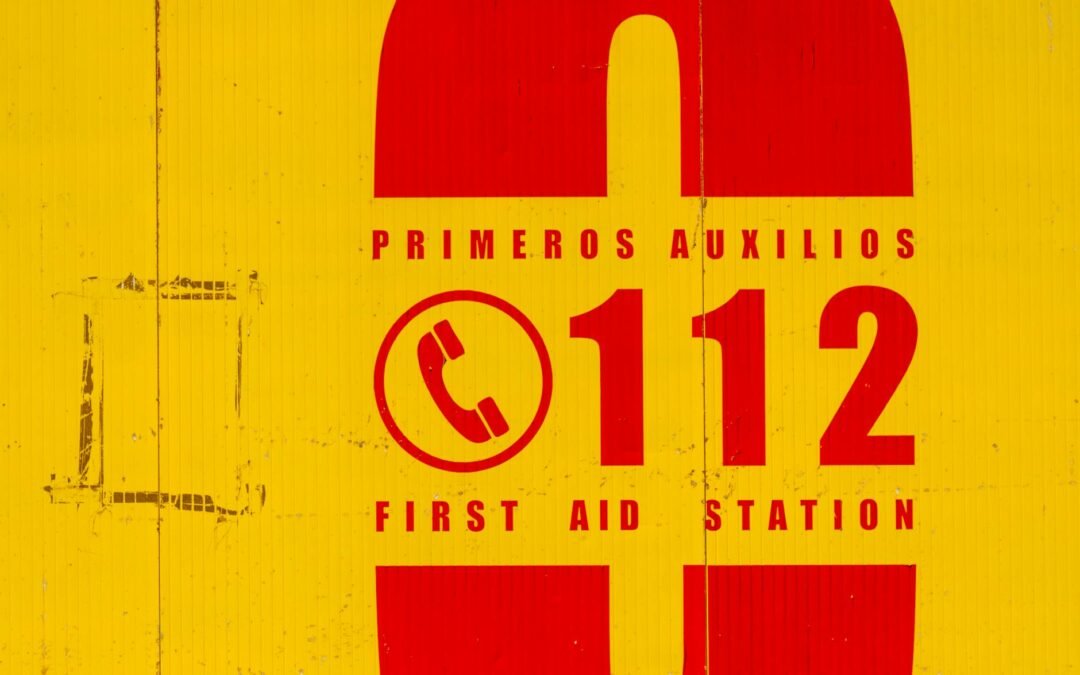 Emergency contact sign for first aid station, featuring phone number 112.