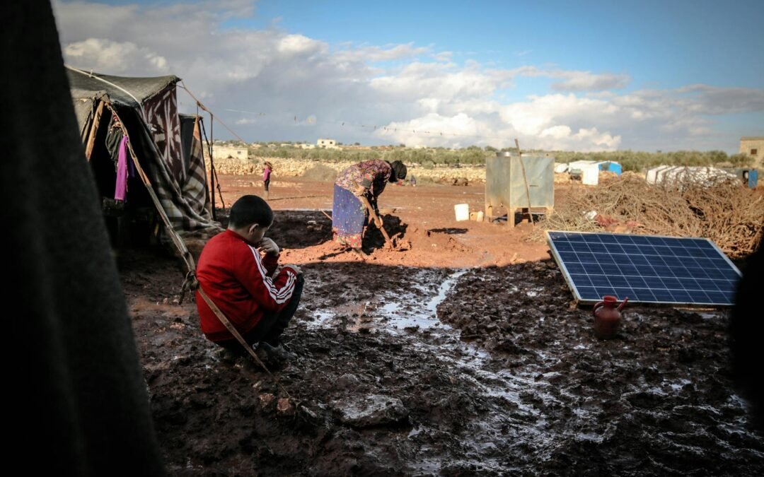 Children and families in a muddy refugee camp seeking immigration assistance and support.