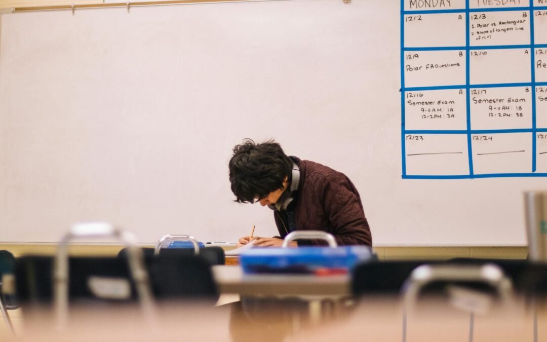 Student studying at a desk, focused on a study schedule in a classroom.