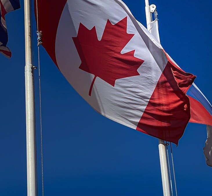 Canadian flag waving against a blue sky, symbolizing Canada residency and citizenship.