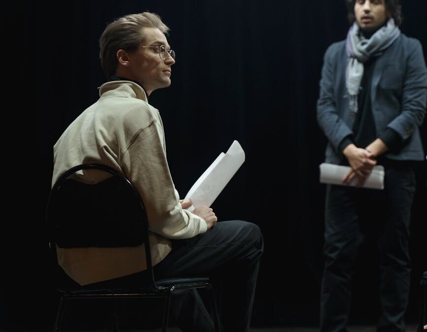 Two actors in discussion, reflecting themes from the Immigration Act in a theatrical setting.