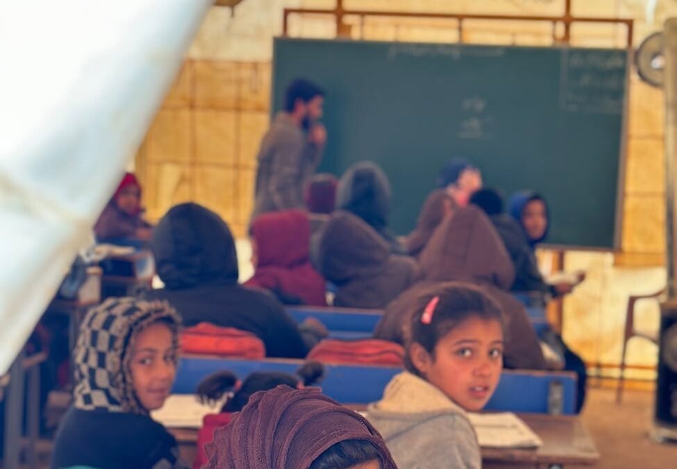 Children in a tent classroom, highlighting refugee education technology initiatives.