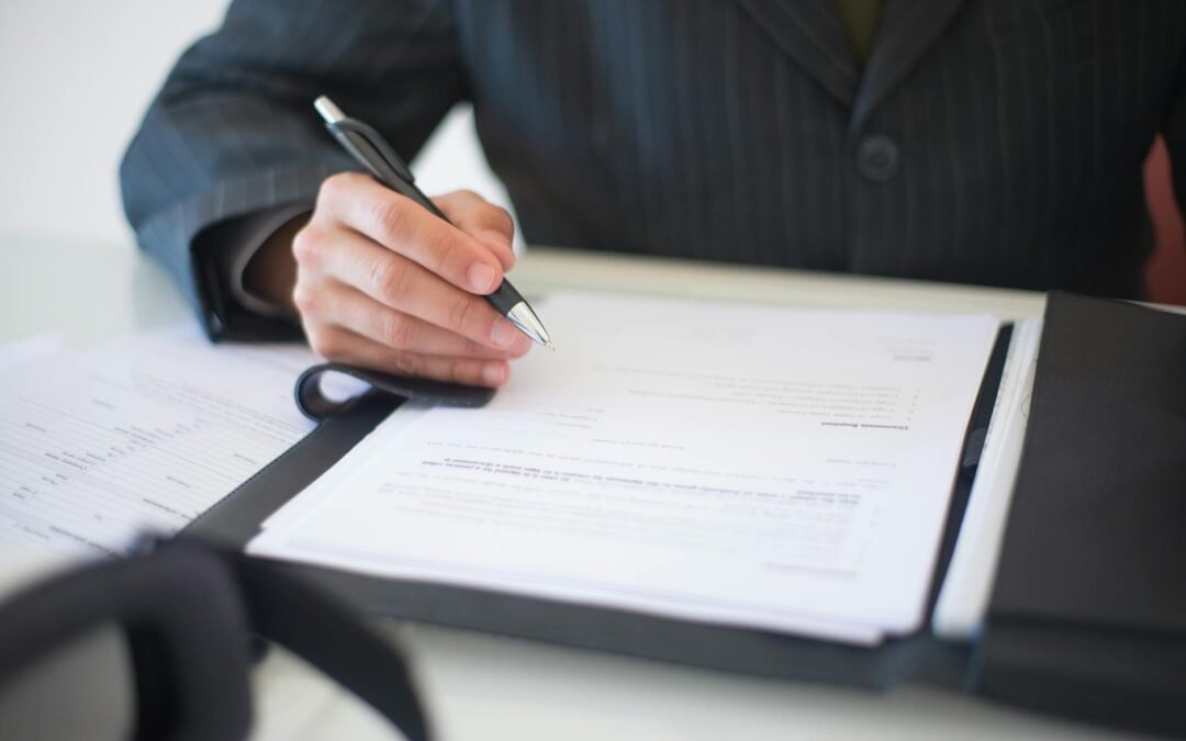 Person reviewing a document checklist with paperwork and pen on a table.