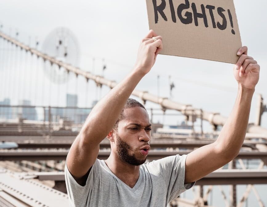 Person holding a sign reading "Human Rights!" during a protest for Canadian citizenship.