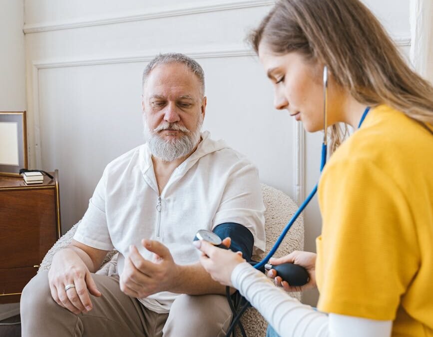 Health care tips: caregiver monitoring elderly man's blood pressure at home.