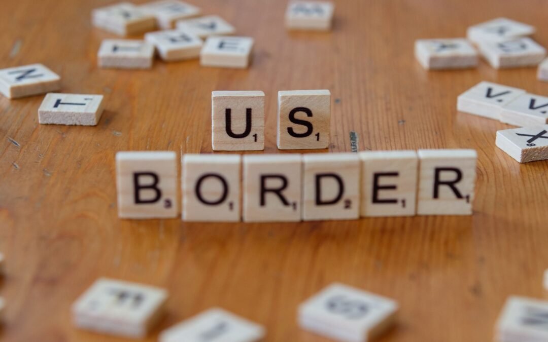 US border tips for immigrants using letter tiles on a wooden table.