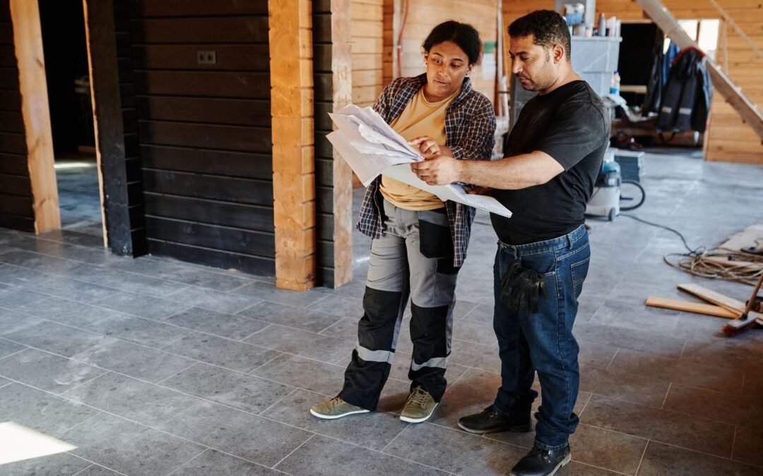 Two skilled workers reviewing construction plans in a home renovation setting.