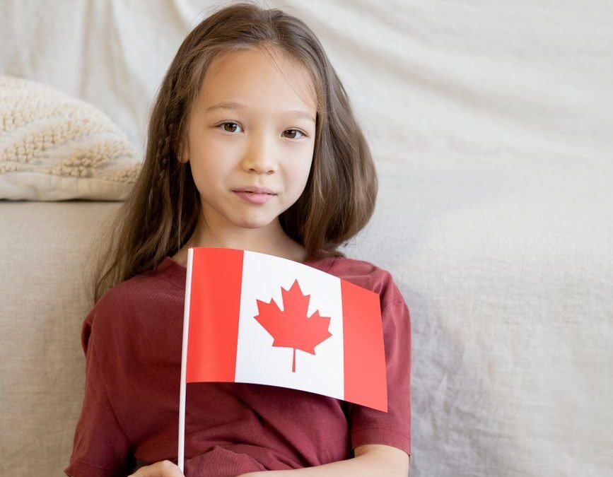 Young girl holding a Canadian flag, symbolizing family sponsorship in Canada.